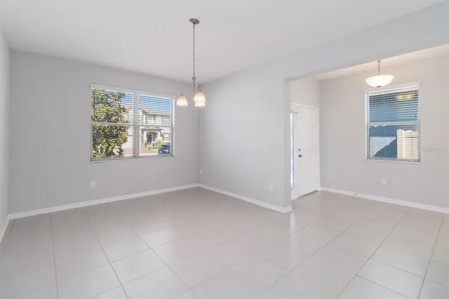 a view of an empty room with window and chandelier fan