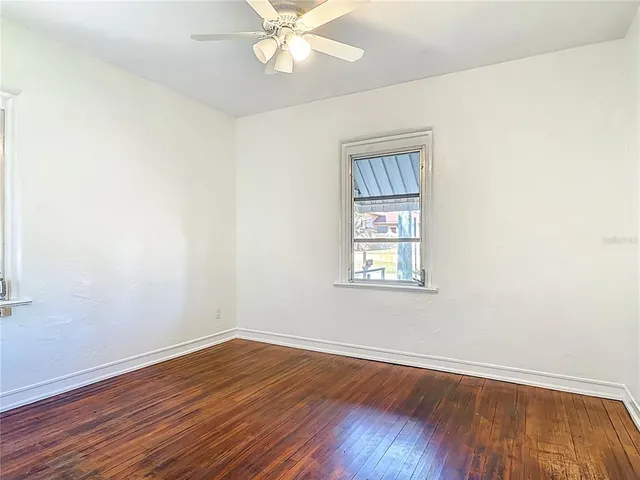 an empty room with wooden floor closet and windows