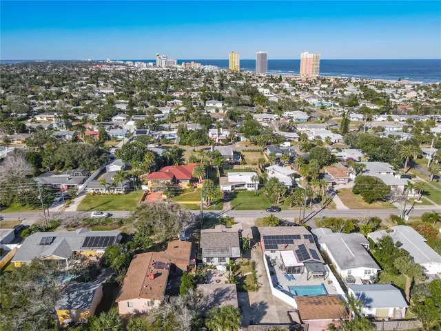 an aerial view of a city with lots of residential buildings and ocean view in back