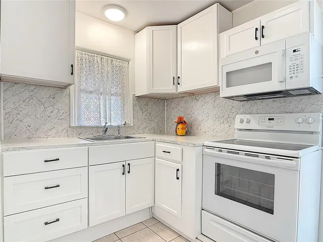 a kitchen with granite countertop white cabinets white stainless steel appliances and a sink