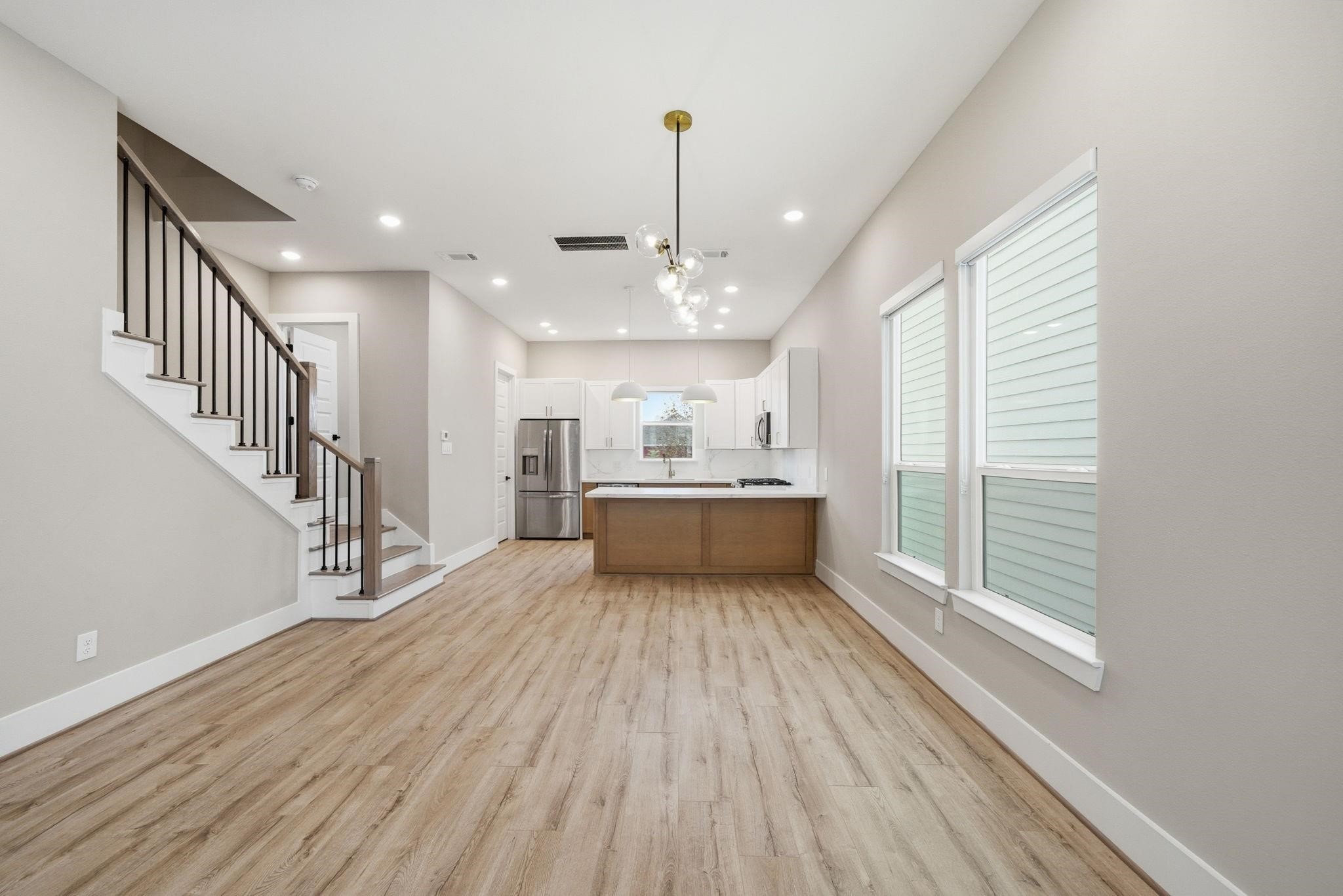 4013 Griggs Road, Unit F Houston, TX 77021 - Photo 25 of 35 Modern open-concept living area with sleek hardwood floors, featuring a stylish kitchen with stainless steel appliances and a large island. Bright natural light streams through the windows, complementing the contemporary design.