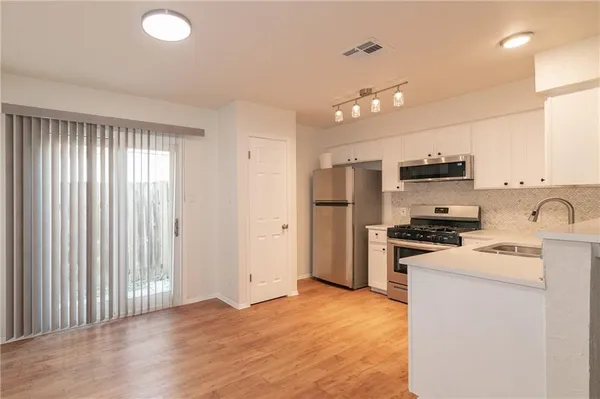 a kitchen with stainless steel appliances granite countertop a refrigerator a stove a sink dishwasher and a microwave with wooden floor