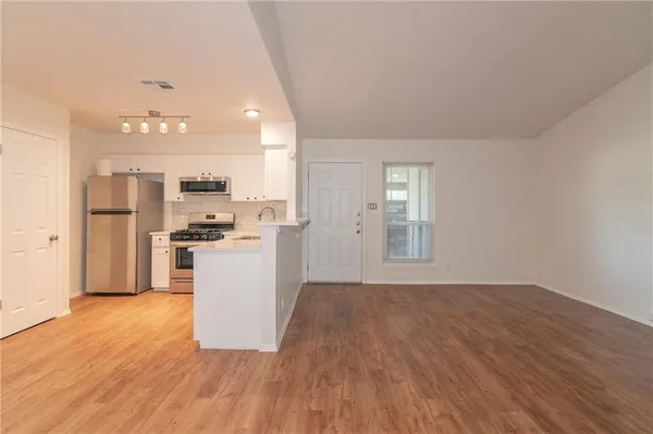 a view of kitchen with refrigerator microwave and stove top oven