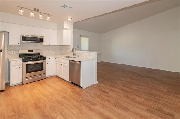 a large kitchen with stainless steel appliances granite countertop a stove a sink and a microwave
