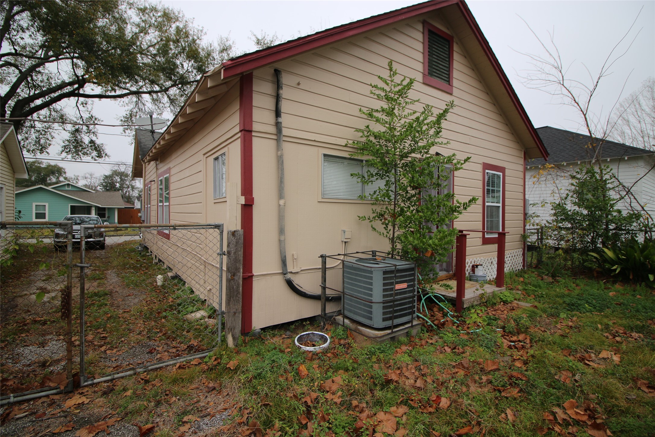 418 3rd Street Humble, TX 77338 - Photo 17 of 20 This photo shows the side view of a modest single-story house with beige siding and red trim. The yard is fenced. The home has central air conditioning .