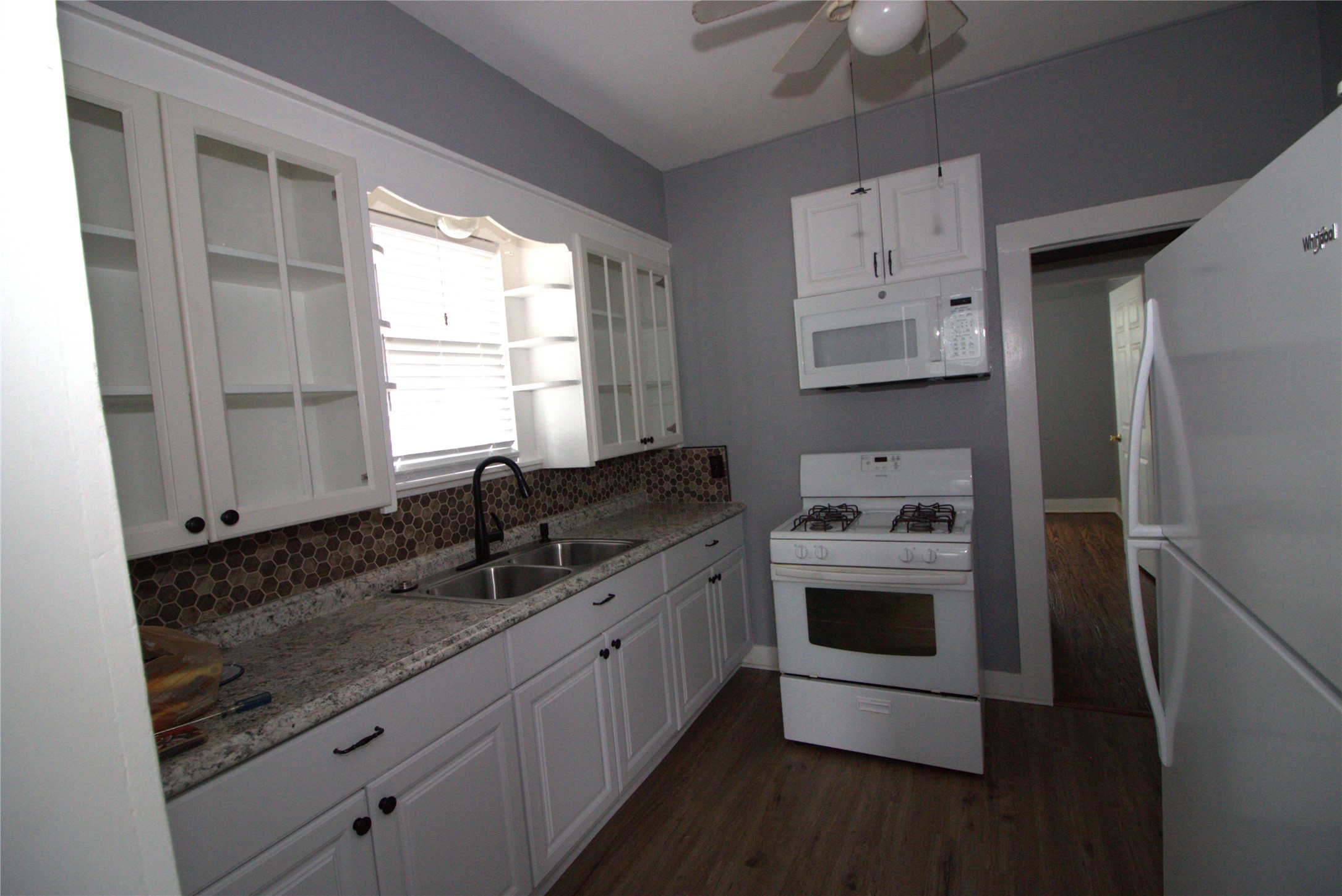418 3rd Street Humble, TX 77338 - Photo 6 of 20 Discover a kitchen designed for functionality, featuring stylish glass cabinets and smooth soft-closing drawers & microwave.