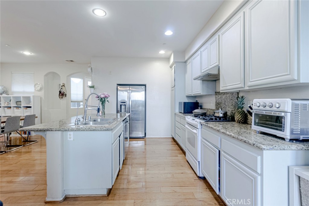 25562 Huxley Drive Stevenson Ranch, CA 91381 - Photo 4 of 24 a large kitchen with stainless steel appliances kitchen island granite countertop a large counter top and a stove
