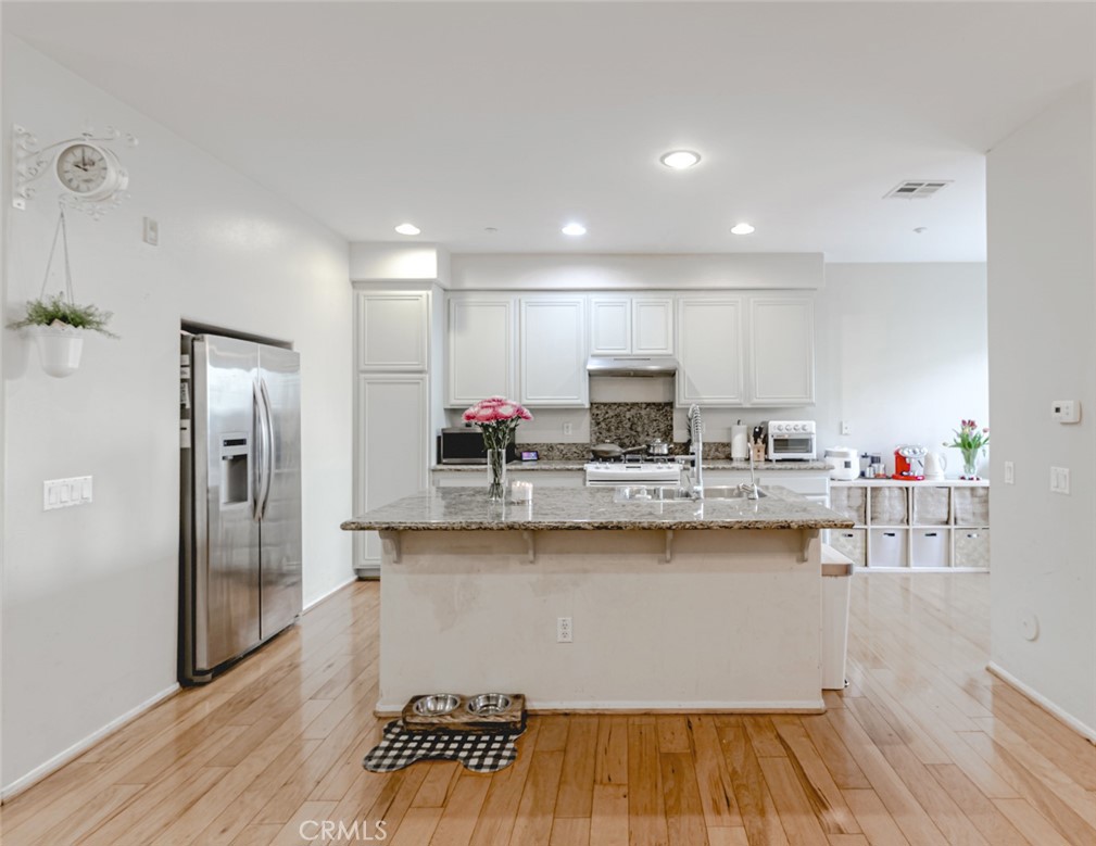 25562 Huxley Drive Stevenson Ranch, CA 91381 - Photo 5 of 24 a kitchen with stainless steel appliances a sink a refrigerator and wooden floor