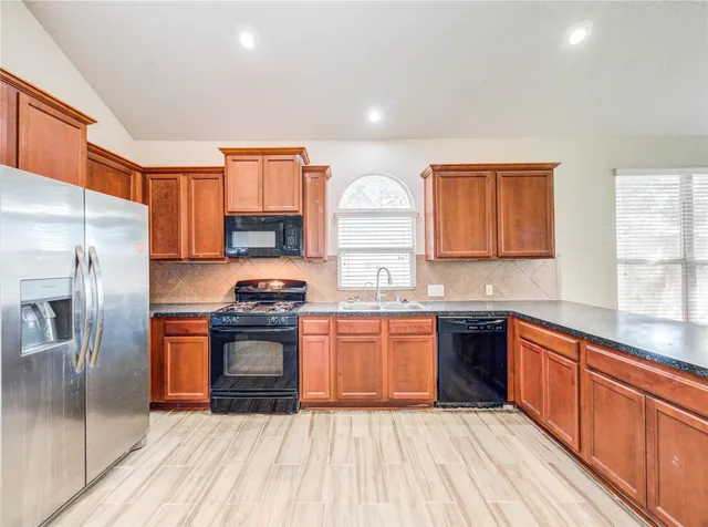 a kitchen with stainless steel appliances granite countertop a sink stove and refrigerator