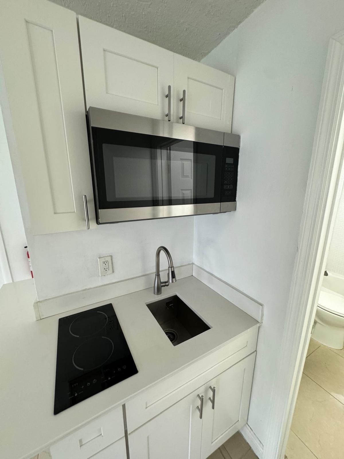 512 Southwest 2nd Street, Unit A Hallandale Beach, FL 33009 - Photo 11 of 13 a kitchen with granite countertop white cabinets and black appliances