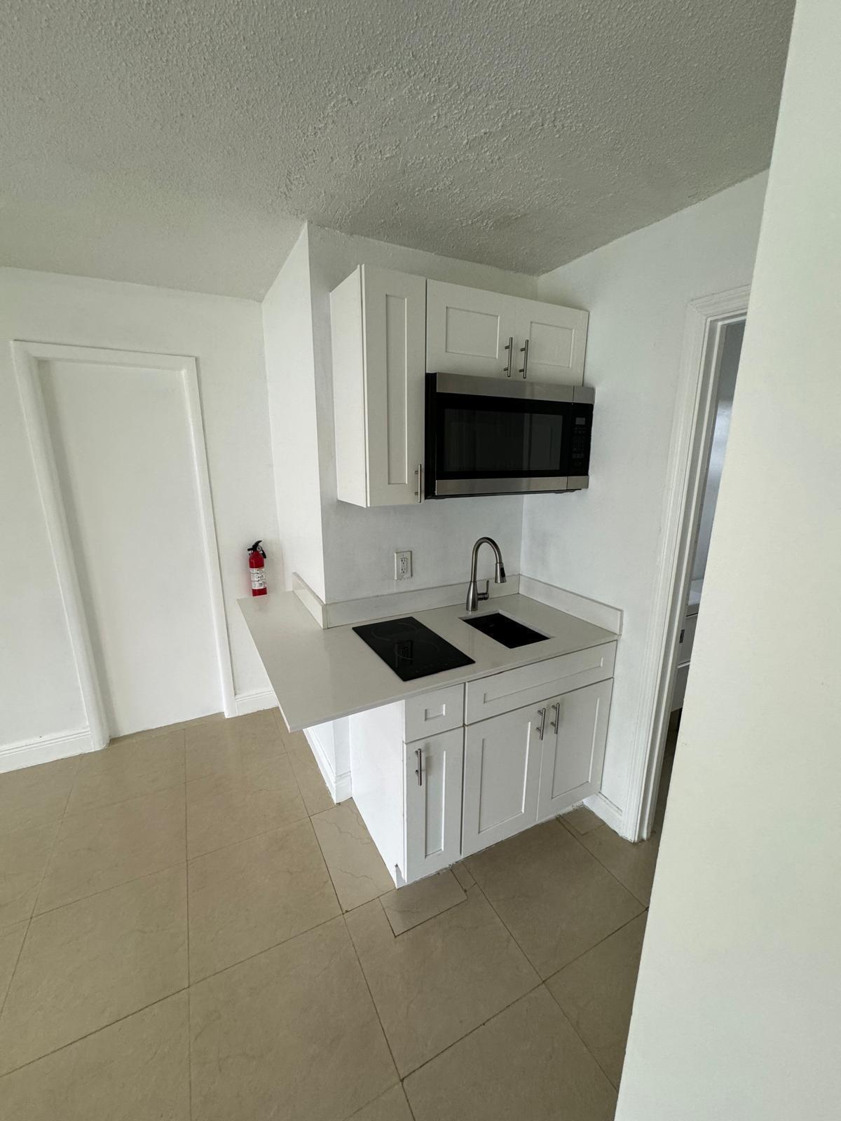 512 Southwest 2nd Street, Unit A Hallandale Beach, FL 33009 - Photo 7 of 13 a kitchen with stainless steel appliances a stove a sink a microwave a refrigerator and cabinets