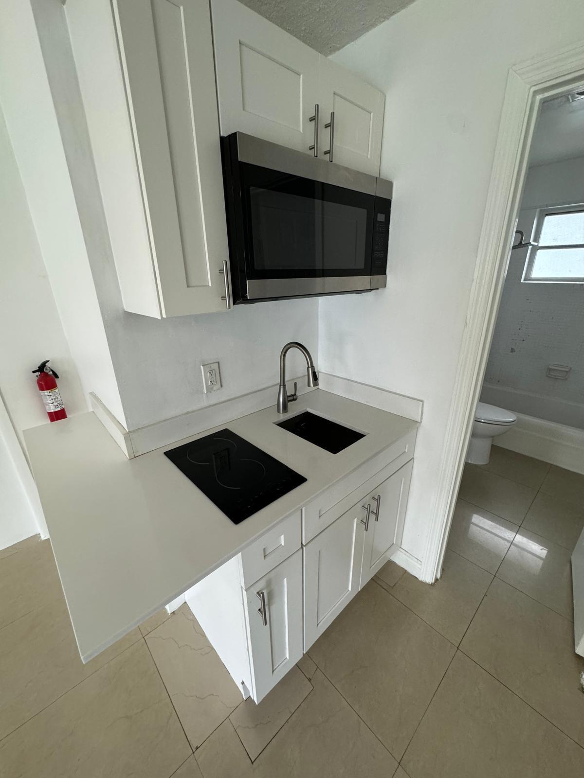 512 Southwest 2nd Street, Unit A Hallandale Beach, FL 33009 - Photo 8 of 13 a kitchen with stainless steel appliances a sink a microwave a stove and a microwave