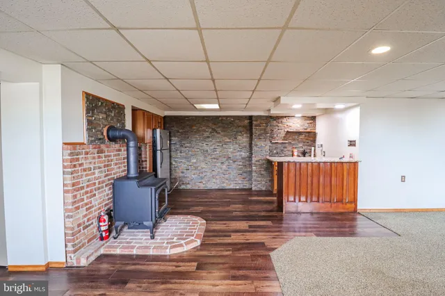 a living room with stainless steel appliances furniture a fireplace and a projector screen
