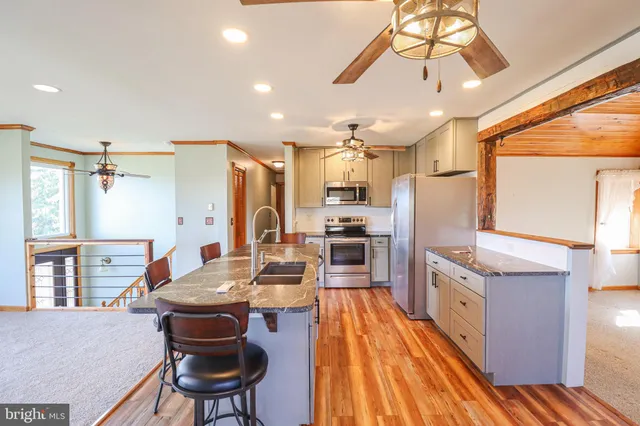 a kitchen with stainless steel appliances kitchen island granite countertop a table chairs in it and wooden floors