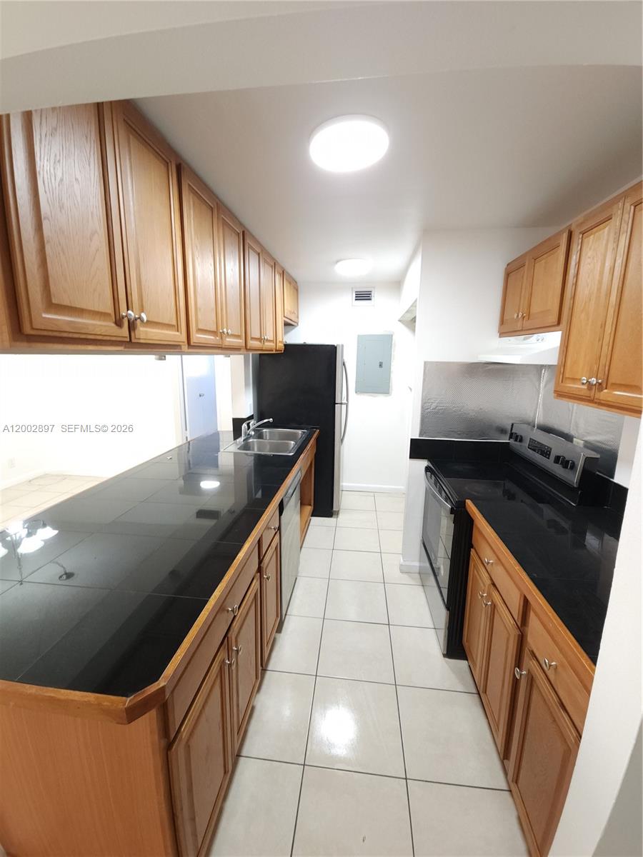 4505 Treehouse Lane, Unit 8H Tamarac, FL 33319 - Photo 24 of 29 a kitchen with granite countertop a stove top oven and cabinets