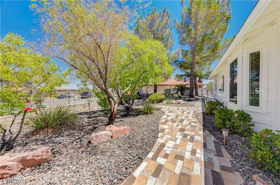 7631 Bermuda Road Las Vegas, NV 89123 - Photo 8 of 64 A winding paver walkway leads to a bright home, framed by desert landscaping and tall trees.