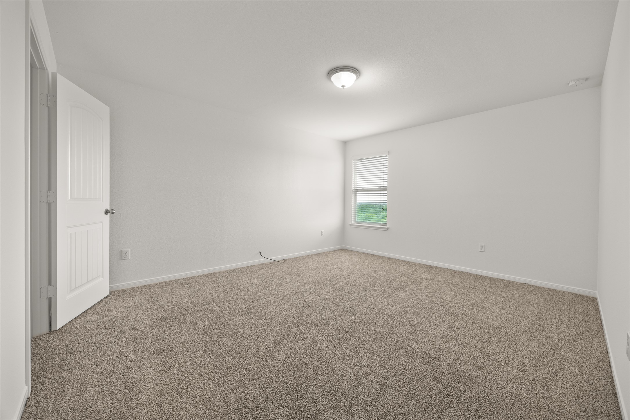 703 Liard River Road Hutto, TX 78634 - Photo 14 of 16 Comfortable carpeted bedroom with a window offering ample light.
