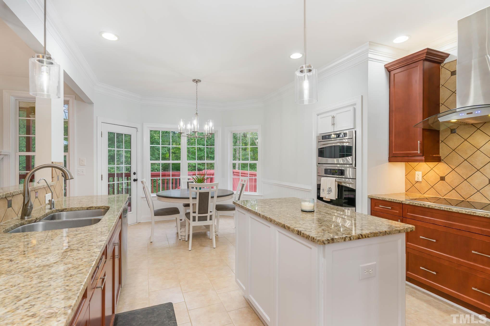 320 Government Road Clayton, NC 27520 - Photo 16 of 48 a dining hall with stainless steel appliances granite countertop a sink dishwasher a stove and a dining table with wooden floor