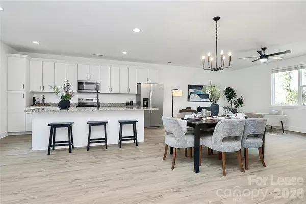a kitchen with stainless steel appliances kitchen island granite countertop a table chairs and a refrigerator