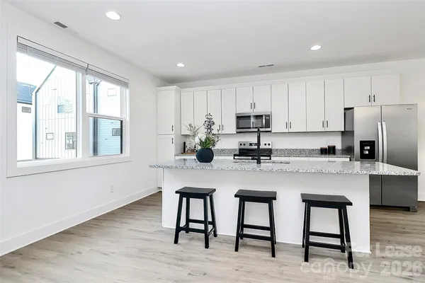 a kitchen with stainless steel appliances granite countertop a table chairs sink refrigerator and cabinets