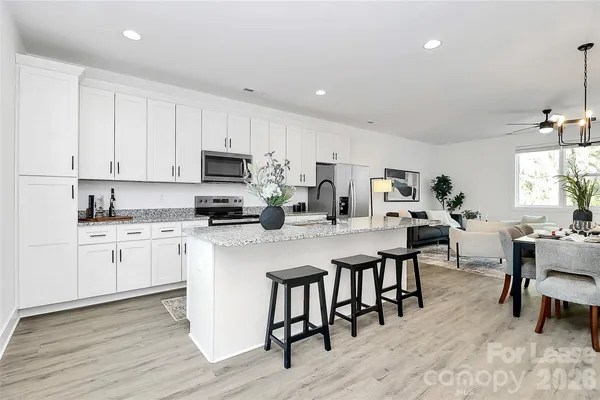 a kitchen with stainless steel appliances granite countertop a stove a sink a microwave a dining table and chairs with wooden floor