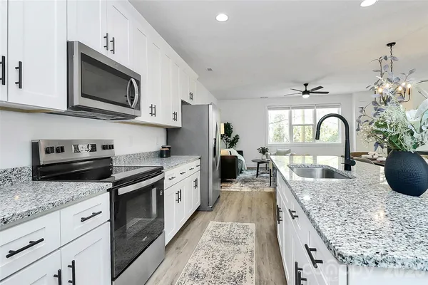 a large kitchen with granite countertop a stove and a sink