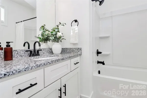 a bathroom with a granite countertop sink a mirror and shower