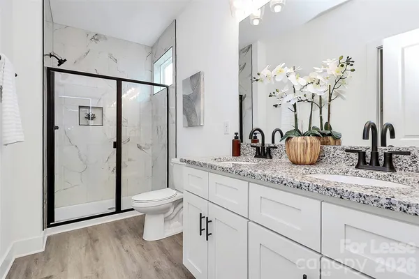a bathroom with a granite countertop sink a toilet and a shower