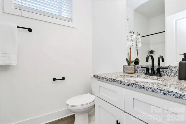 a bathroom with a granite countertop sink a toilet and mirror