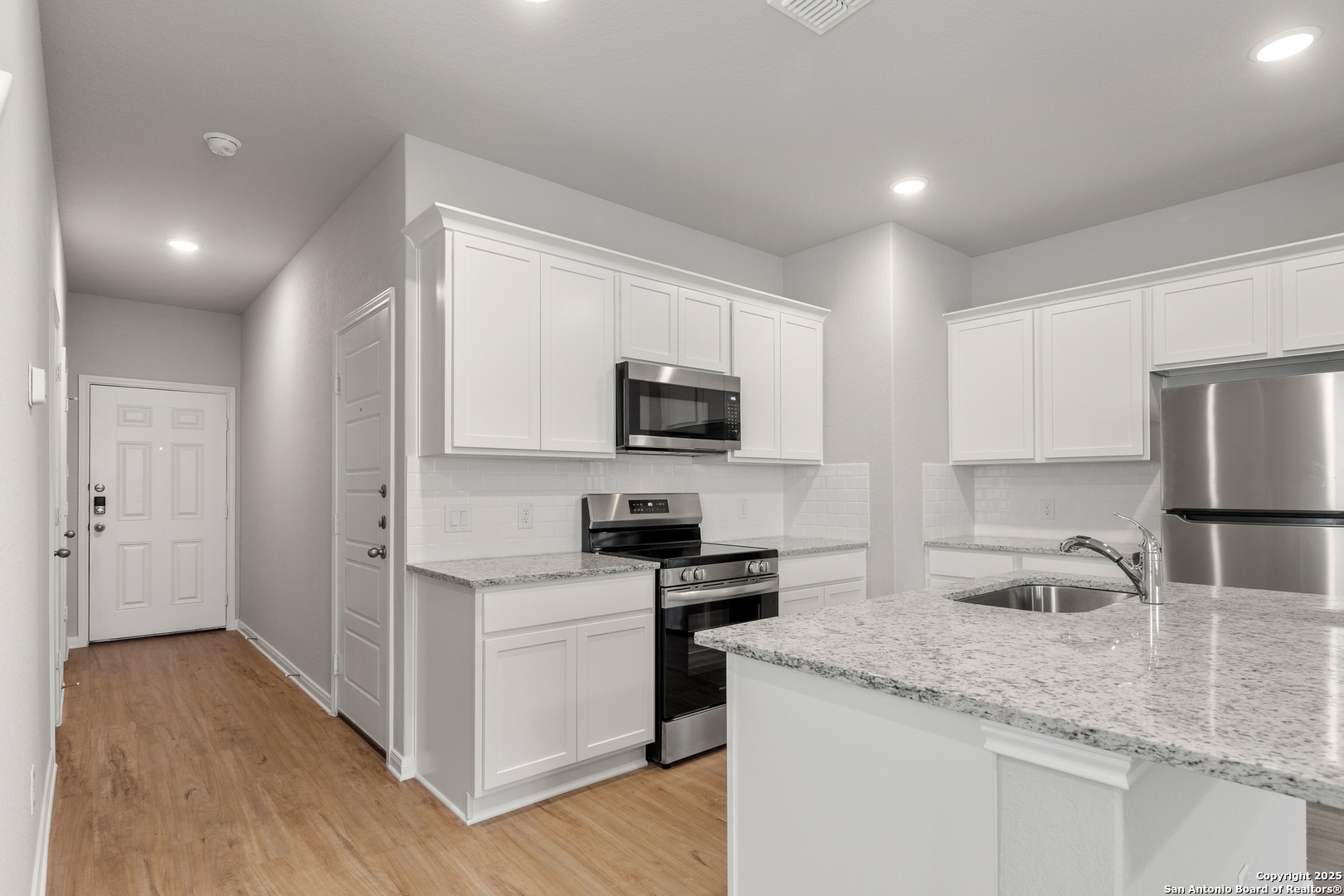 3928 Abbott Pass, Unit 101 St. Hedwig, TX 78152 - Photo 7 of 17 a kitchen with granite countertop a sink stainless steel appliances and white cabinets