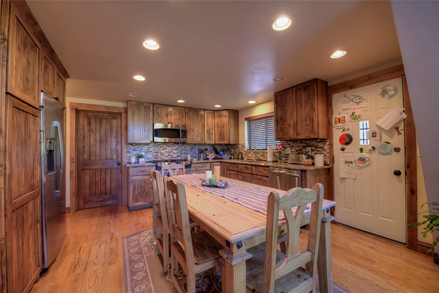 511 Vail Circle Dillon, CO 80435 - Photo 44 of 47 a kitchen with stainless steel appliances a refrigerator a stove a sink dishwasher and a dining table with wooden floor