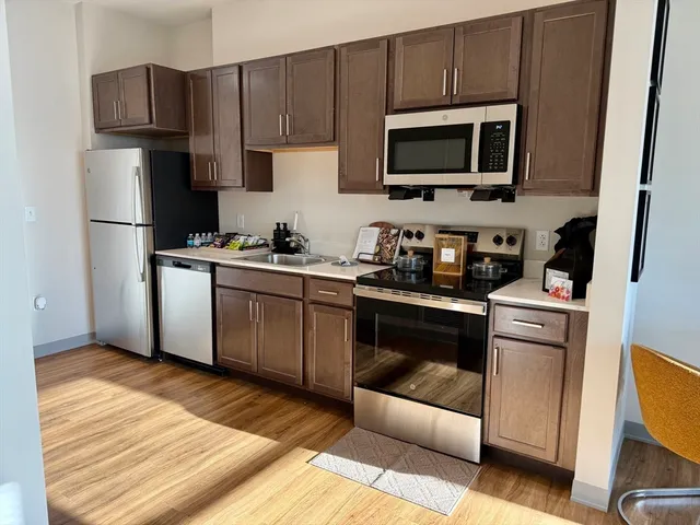 a kitchen with cabinets stainless steel appliances and wooden floor