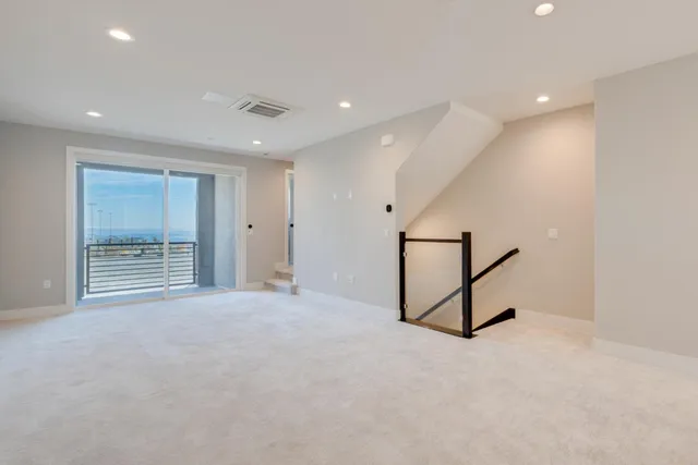 a view of an empty room with window and a ceiling fan