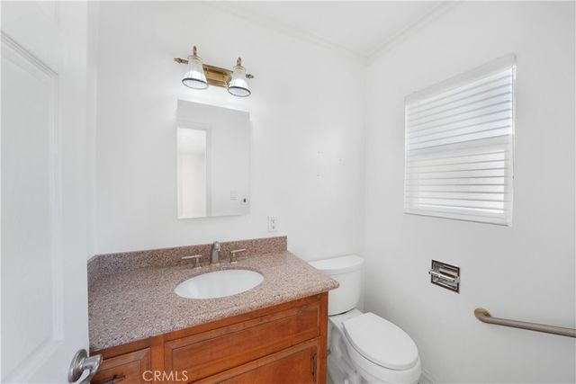 a bathroom with a granite countertop sink toilet and mirror