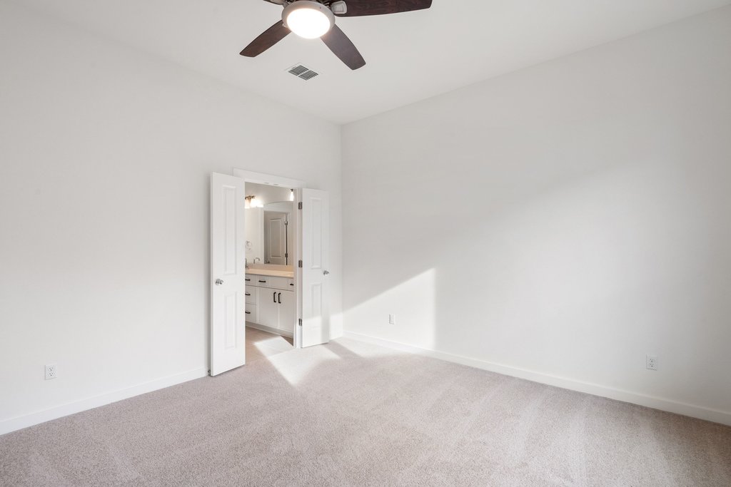 2205 Cento Walk Round Rock, TX 78664 - Photo 9 of 35 Unfurnished bedroom featuring light colored carpet, ensuite bathroom, and a ceiling fan