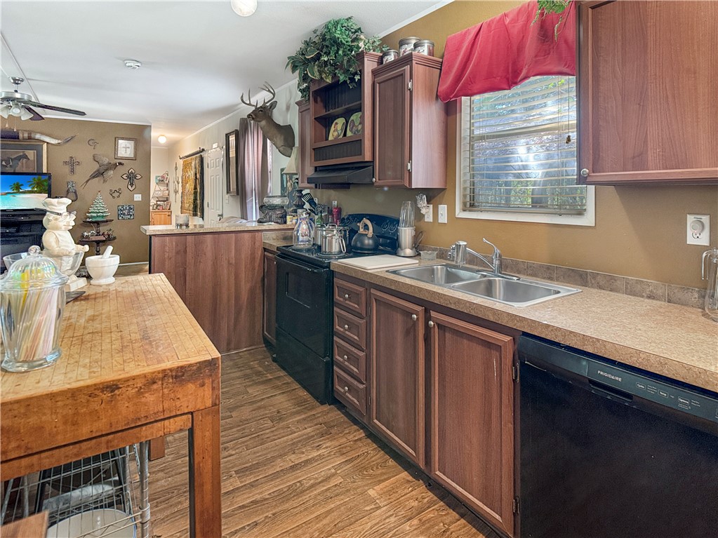 10134 Cobb Branch Road Franklin, TX 77856 - Photo 8 of 23 Kitchen featuring black appliances, dark wood-style flooring, light countertops, open shelves, and a peninsula