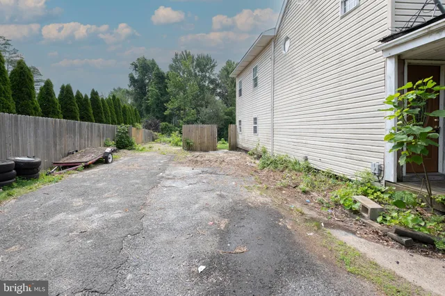 a backyard of a house with plants and trees with wooden fence