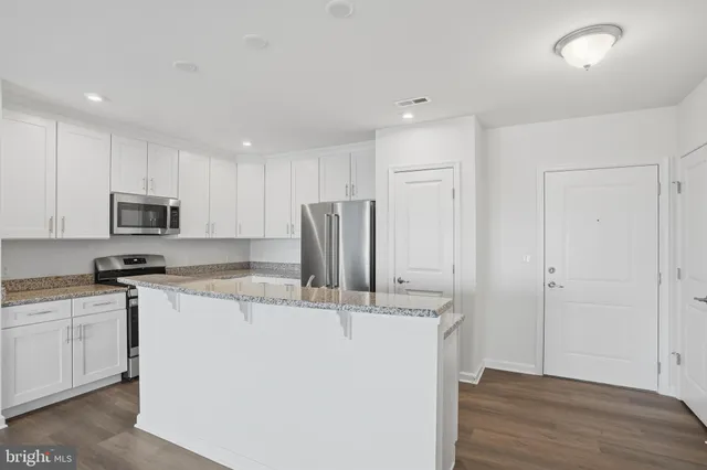 a kitchen with stainless steel appliances granite countertop a refrigerator a sink a stove a microwave and white cabinets