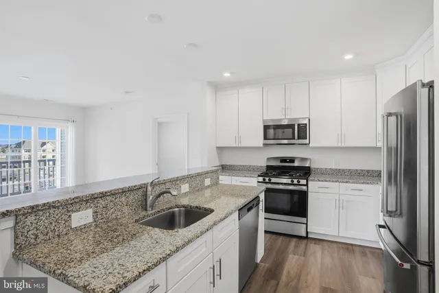 a kitchen with granite countertop a sink stove and refrigerator