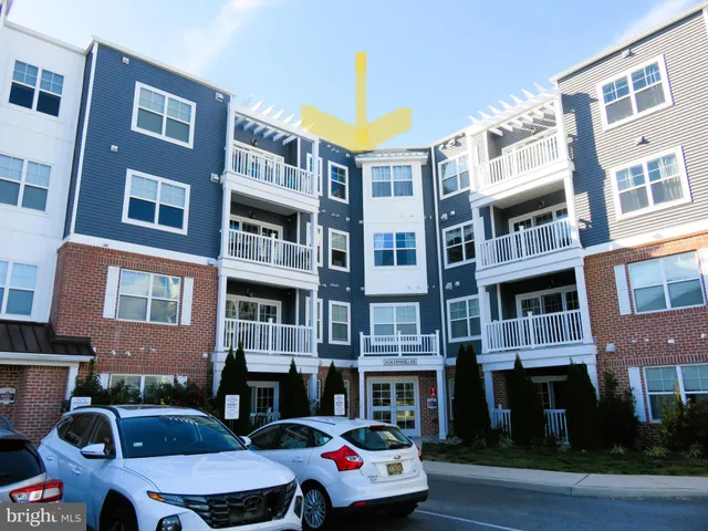 a front view of a building with lot of cars and trees