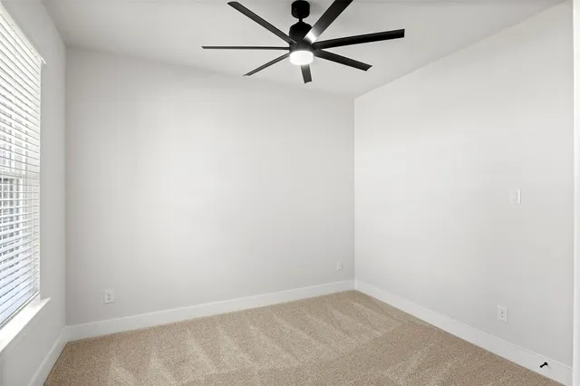 an empty room with a window and a fan