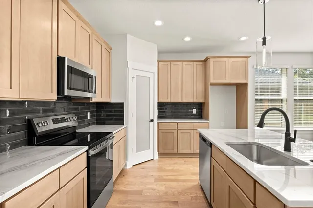 a kitchen with granite countertop a sink stainless steel appliances and white cabinets