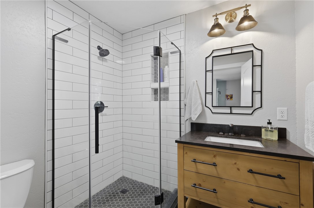 515 Crescent Drive Bryan, TX 77801 - Photo 30 of 43 Shower stall with white subway tile surround, dark hexagonal floor tiles, and clear glass enclosure
