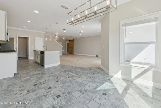 a view of an empty room with window and chandelier fan