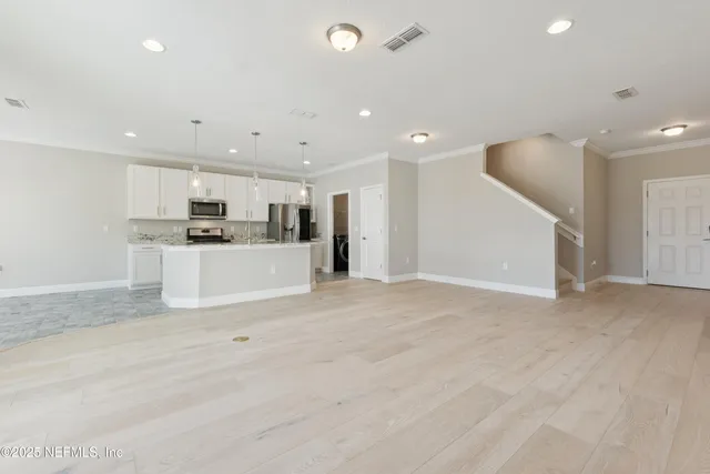 a view of an empty room with wooden floor and stairs