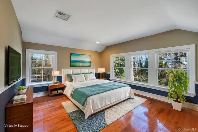 a bedroom with a bed a large window and wooden floor