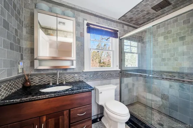 a bathroom with a granite countertop sink mirror vanity and toilet