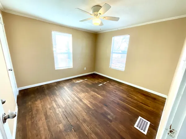 a view of an empty room with window and wooden floor
