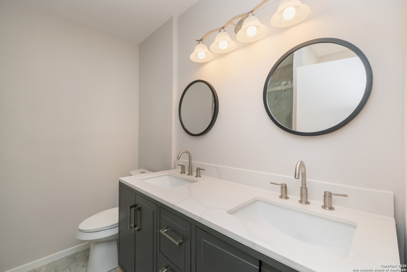8906 Willmon Way Windcrest, TX 78239 - Photo 19 of 34 a bathroom with a toilet sink and mirror