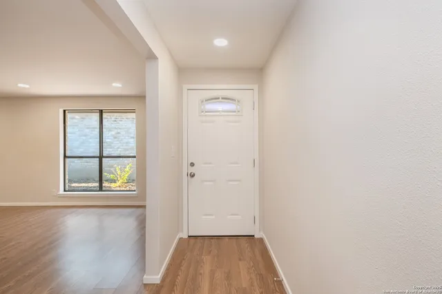 an empty room with wooden floor and windows